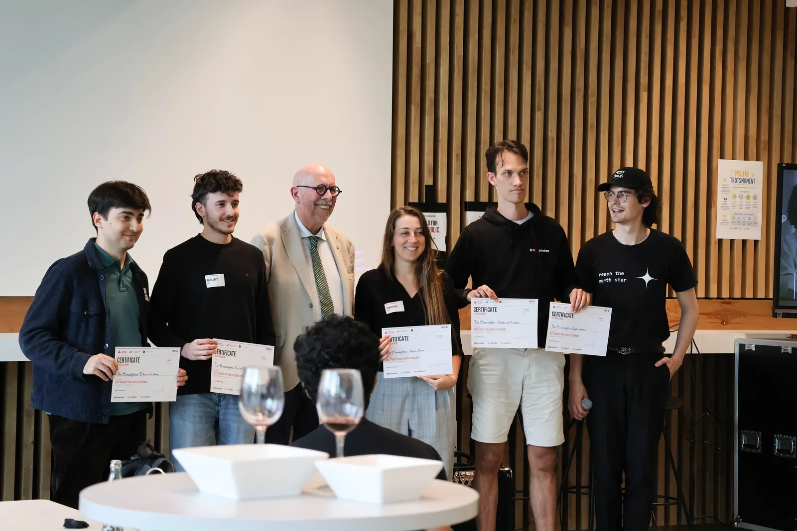 Winnaars van een hackathon staan met hun certificaten naast de juryleden.